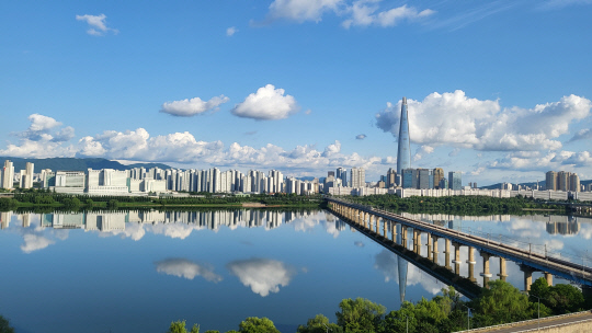 부처님 오신날 황금연휴. 지리하게 내린 빗줄기 만큼이나 아쉬움이 컸다. 한꺼번에 보상하려 했던 것일까. 대체공휴일이자 연휴 마지막날인 29일, 자연은 파아란 하늘을 선물했다. 시리도록 파란 하늘에 자칫 눈을 다칠까 걱정한 때문일까.  희디 흰 구름꽃 몇 송이도 살포시 올려놓았다. 한강은 그 하늘을, 그리고 인간의 탐욕마저  온몸으로 감싸안았다.  서울 광진구 구의동 테크노마트 하늘정원. 강건너 롯데타워와 잠실 아파트 단지, 그리고 한강을 남북으로 잇는 잠실철교의 모습을 휴대전화 카메라에 담았다.           독자 김용진 씨 제공